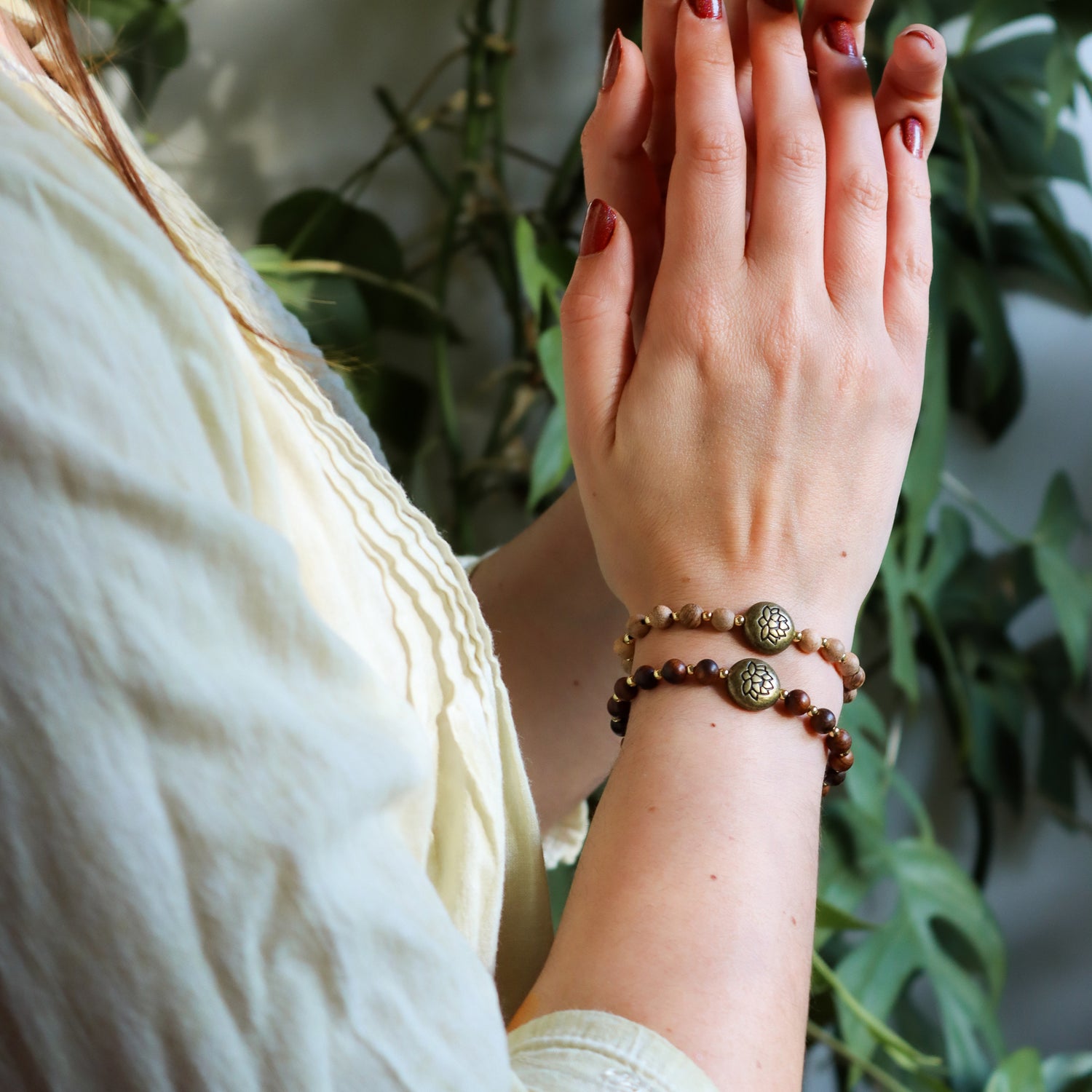 Due bracciali loto legno naturale indossati su polsi femminili con dettagli eleganti