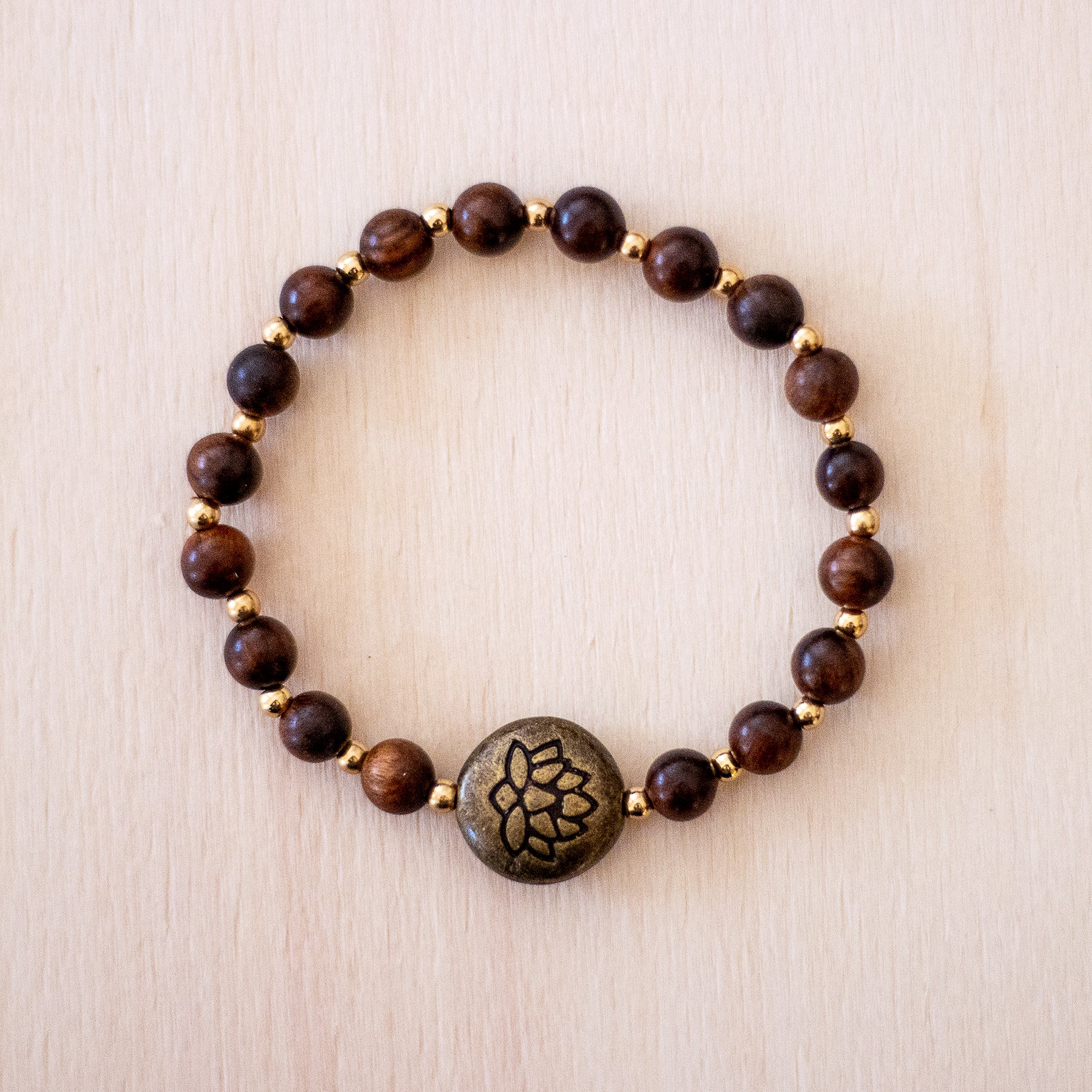 Bracciale loto legno naturale con perline scure e dettagli dorati per uno stile elegante