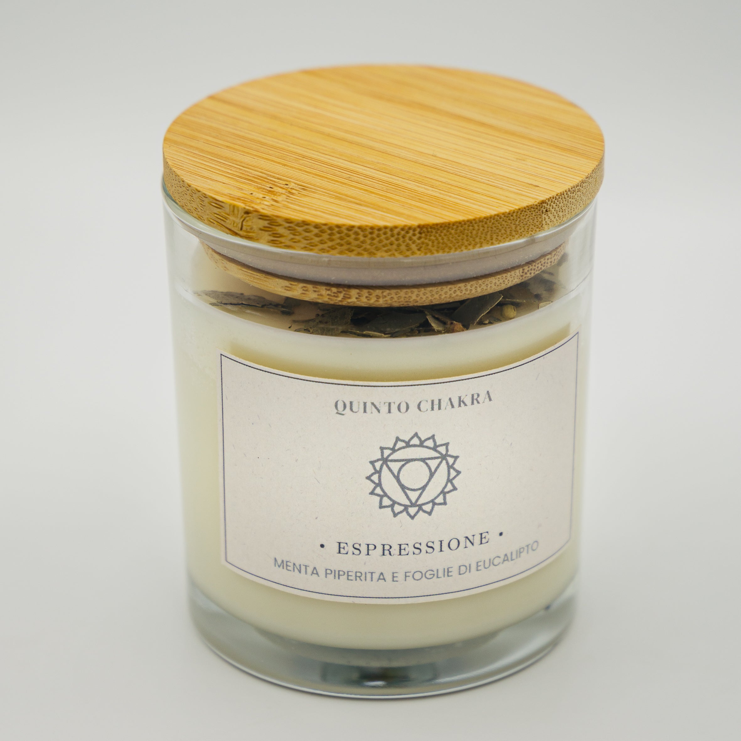 Candela espressione quinto chakra con menta piperita e foglie di eucalipto in contenitore di vetro