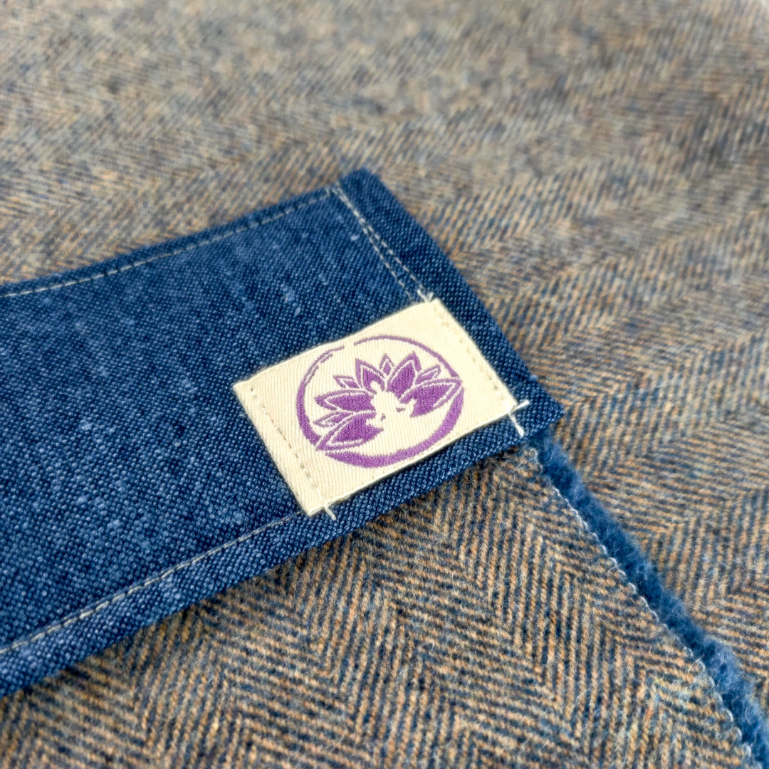 Dettaglio della coperta yoga alpaca con etichetta di Shop Zen in tessuto grigio e blu