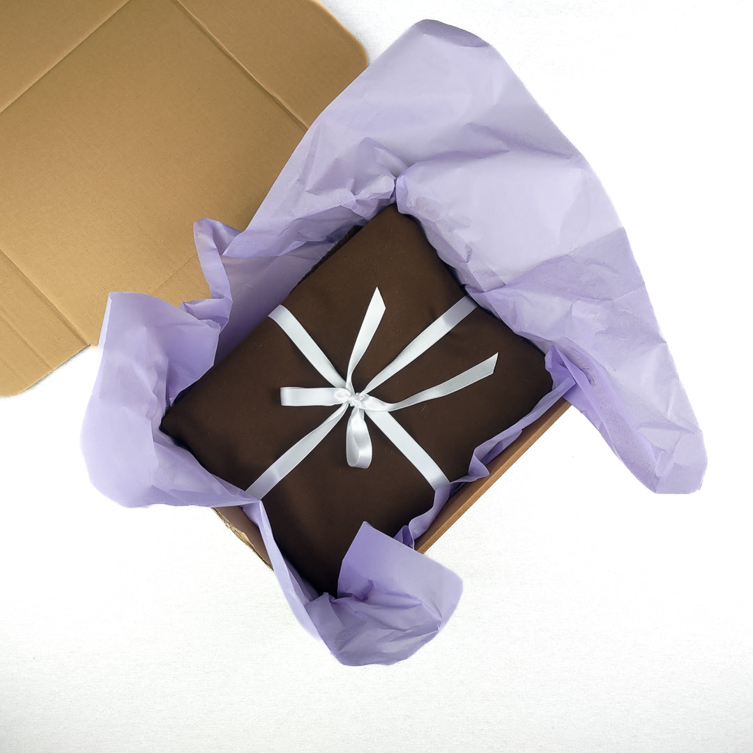 Confezione di coperta yoga lana blu pronta per essere aperta con carta velina e nastro decorativo