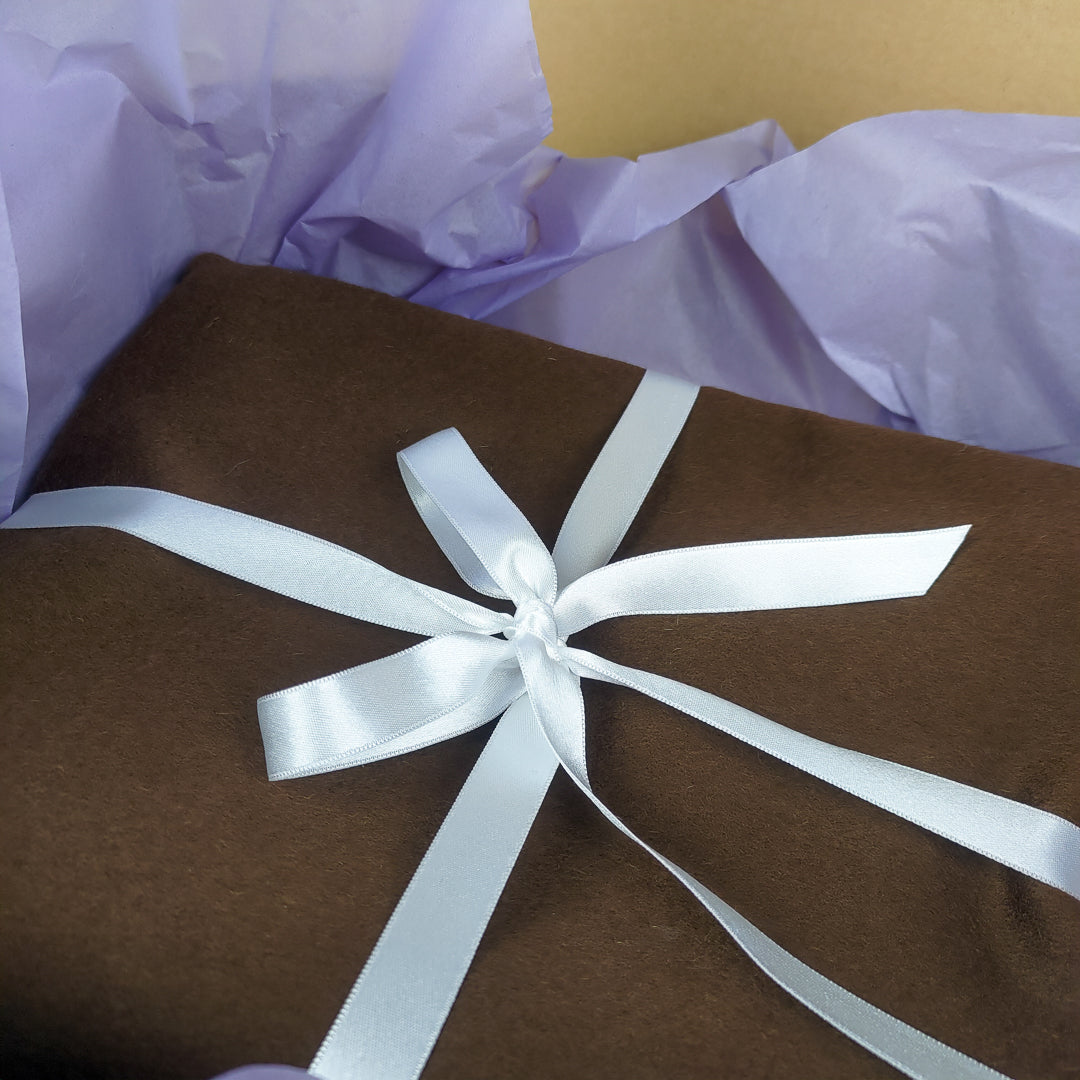 Coperta yoga lana blu avvolta in una bella confezione con nastro bianco per un regalo perfetto