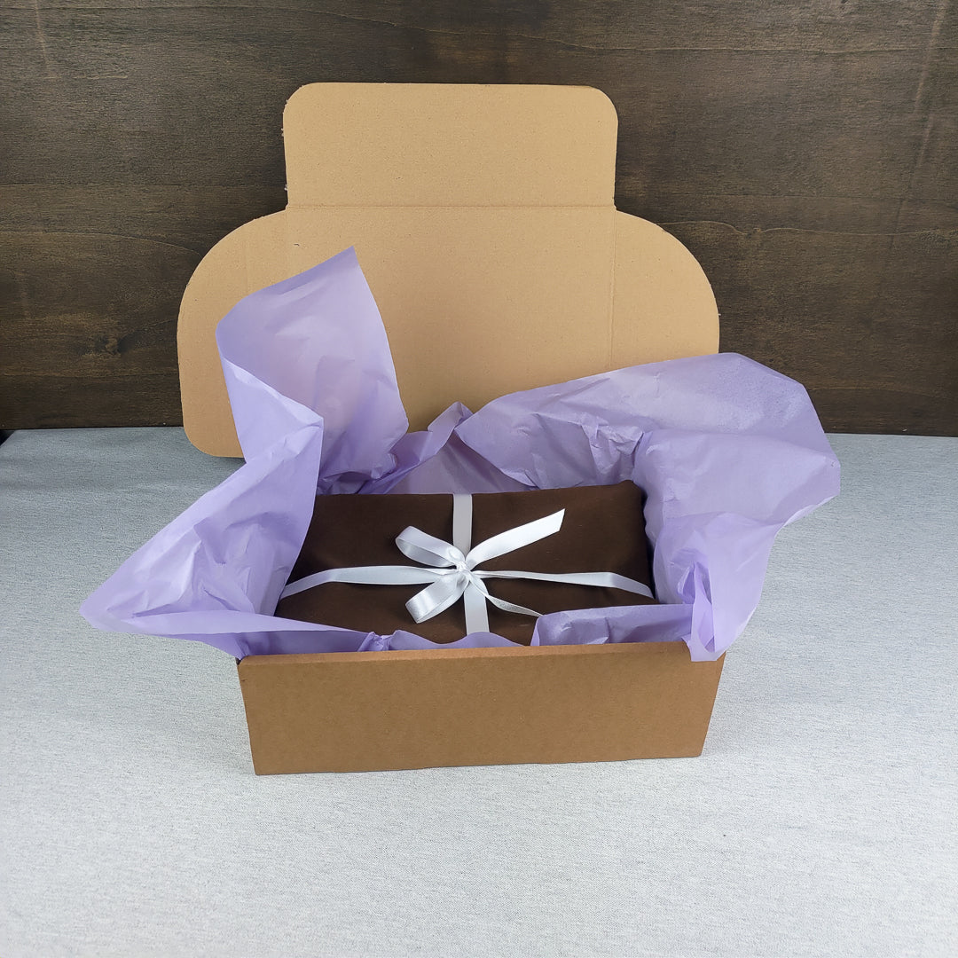 Scatola con coperta yoga lana blu avvolta in carta velina viola per un regalo elegante