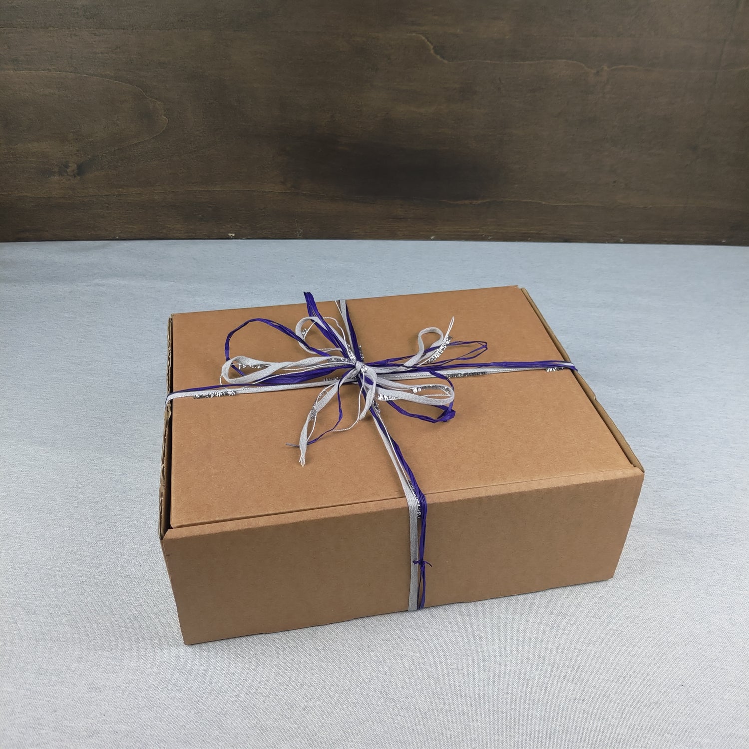 Scatola regalo avvolta con nastro contenente una coperta yoga lana blu di Shop Zen