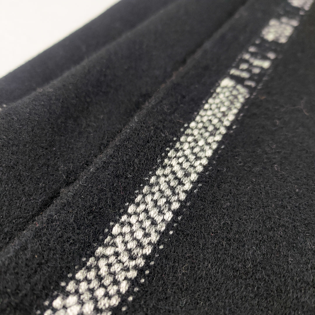 Dettaglio della coperta yoga nera velure con una cucitura bianca elegante per un tocco di stile