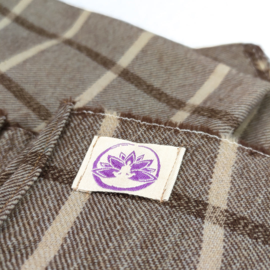 Dettaglio della coperta yoga pura lana merino con design a quadri e etichetta Shop Zen