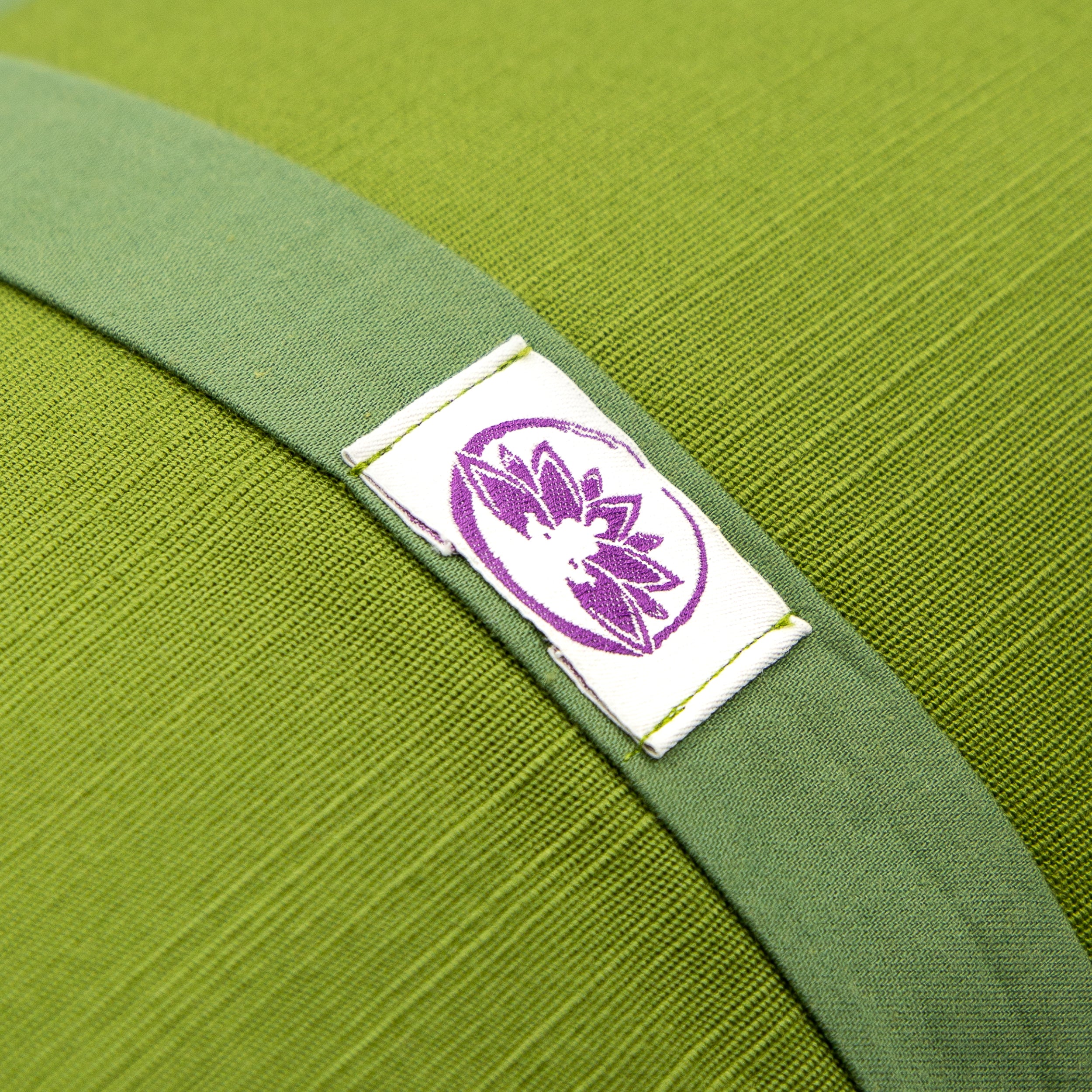 Dettaglio del cuscino Zafu a Mezzaluna verde con etichetta di Shop Zen per supporto lombare