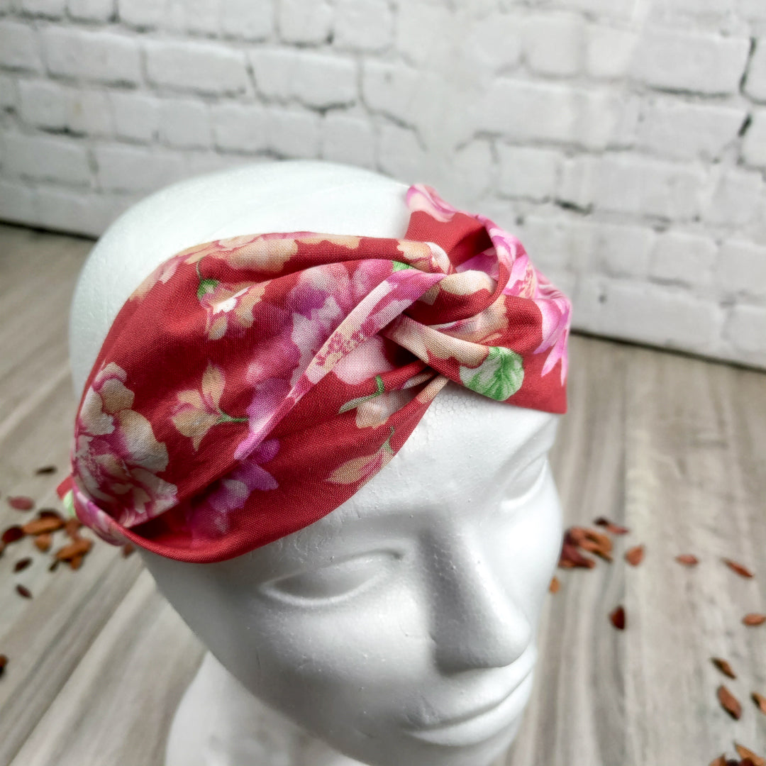 Fascia capelli elastica floreale rosa con design a fiori su fondo rosso per un look elegante