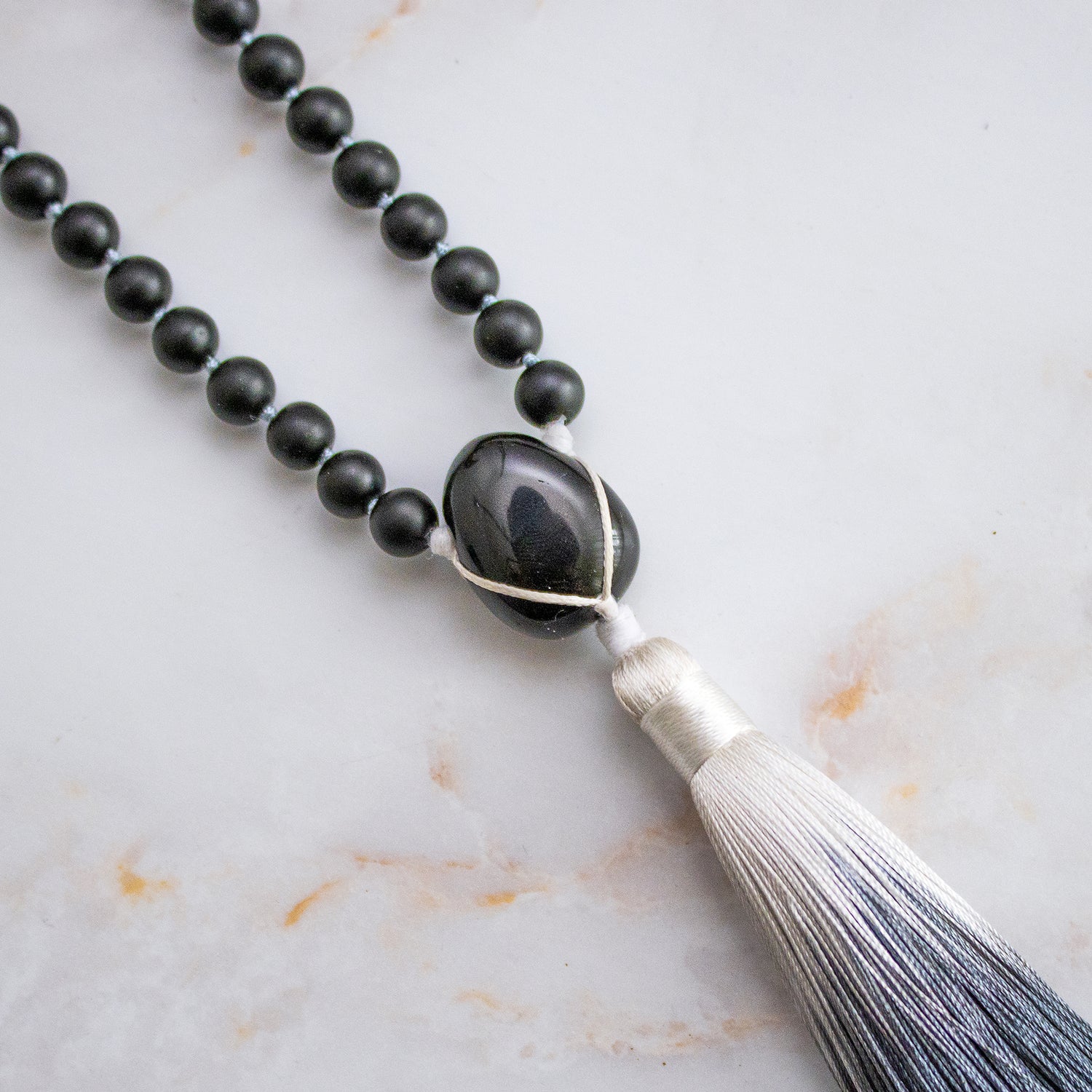 Collana mala ossidiana e howlite con pon-pon grigio e perle nere lucide