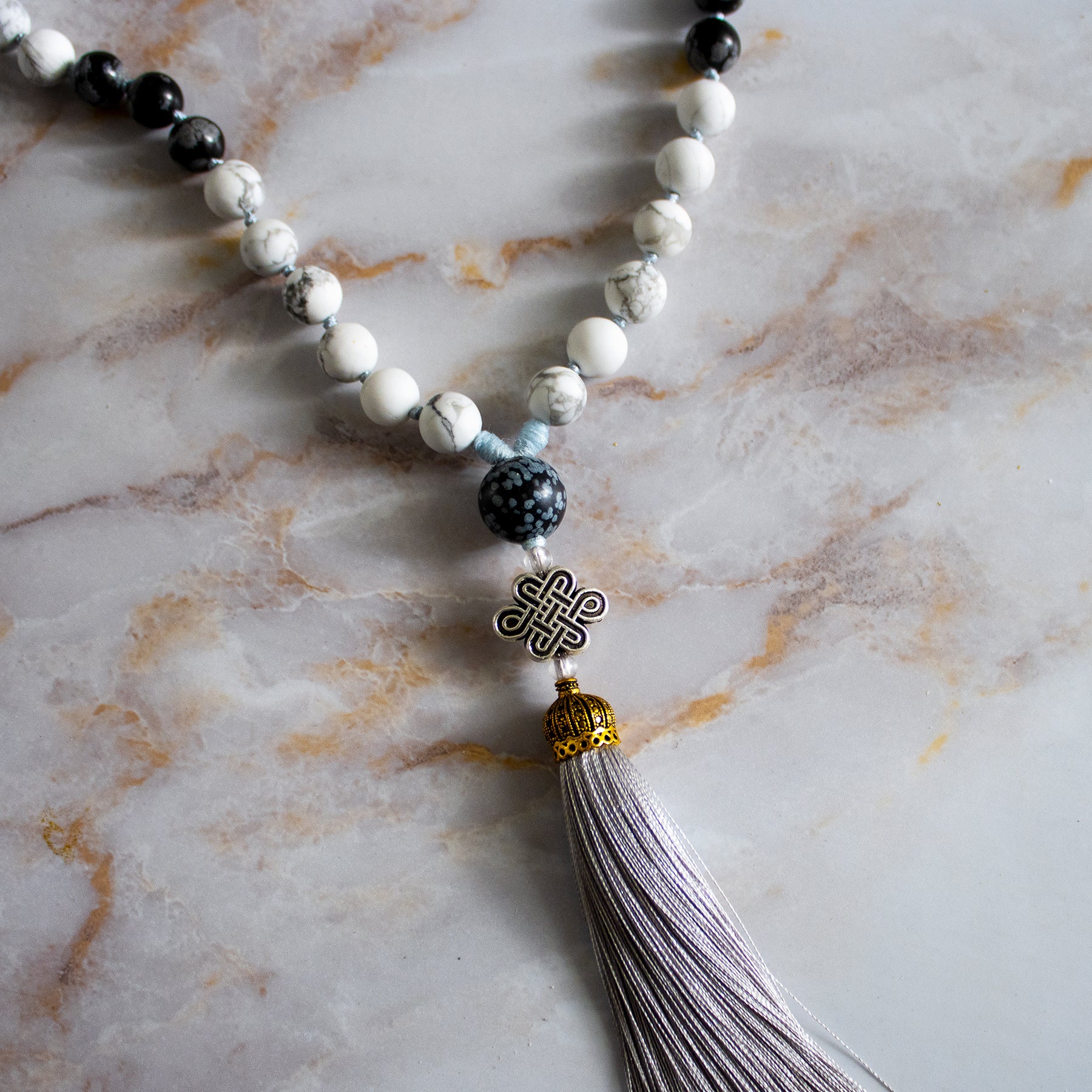 Collana mala ossidiana fiocco di neve con perline bianche e nere e nappina in seta