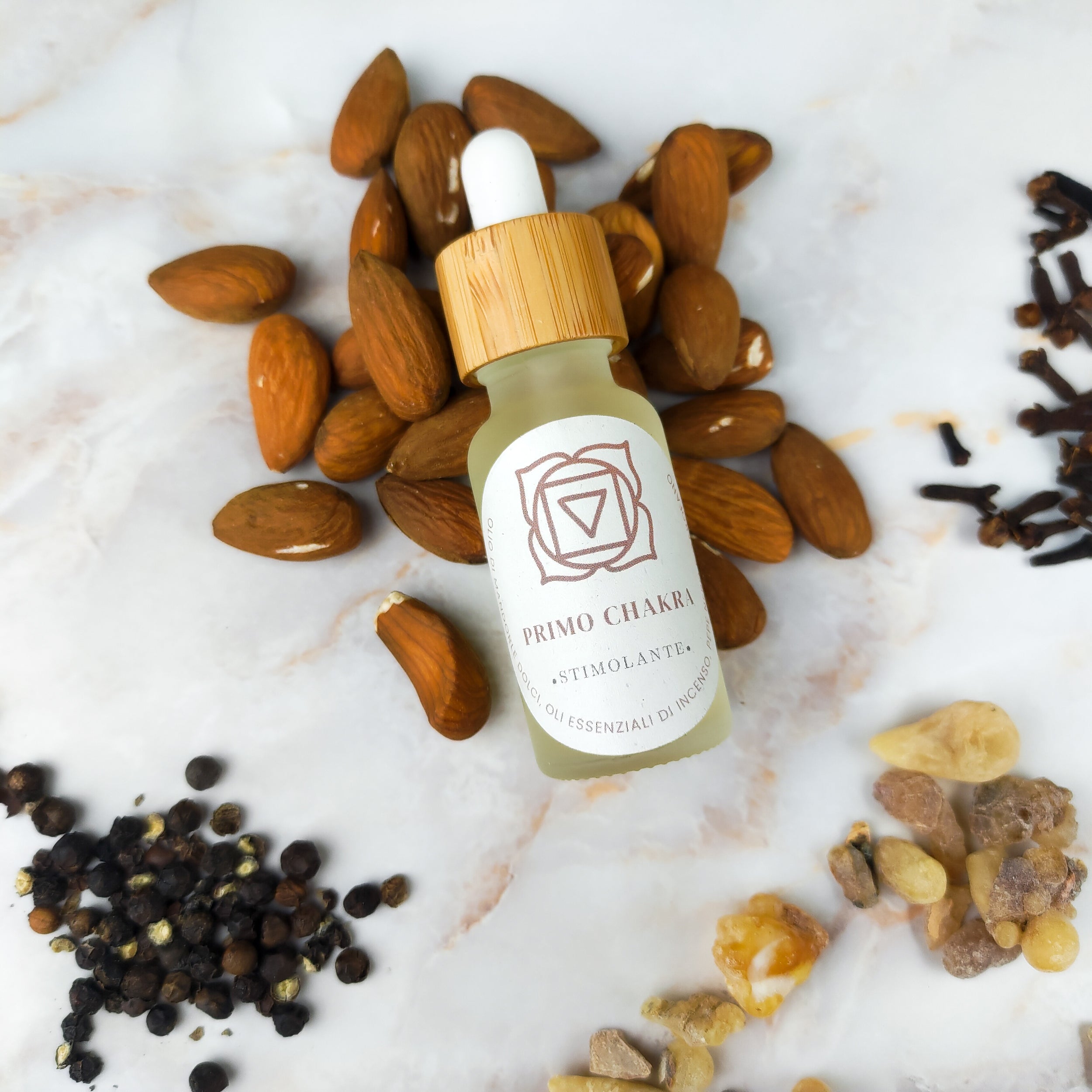 Olio per massaggi primo chakra con oli essenziali e mandorle su fondo bianco