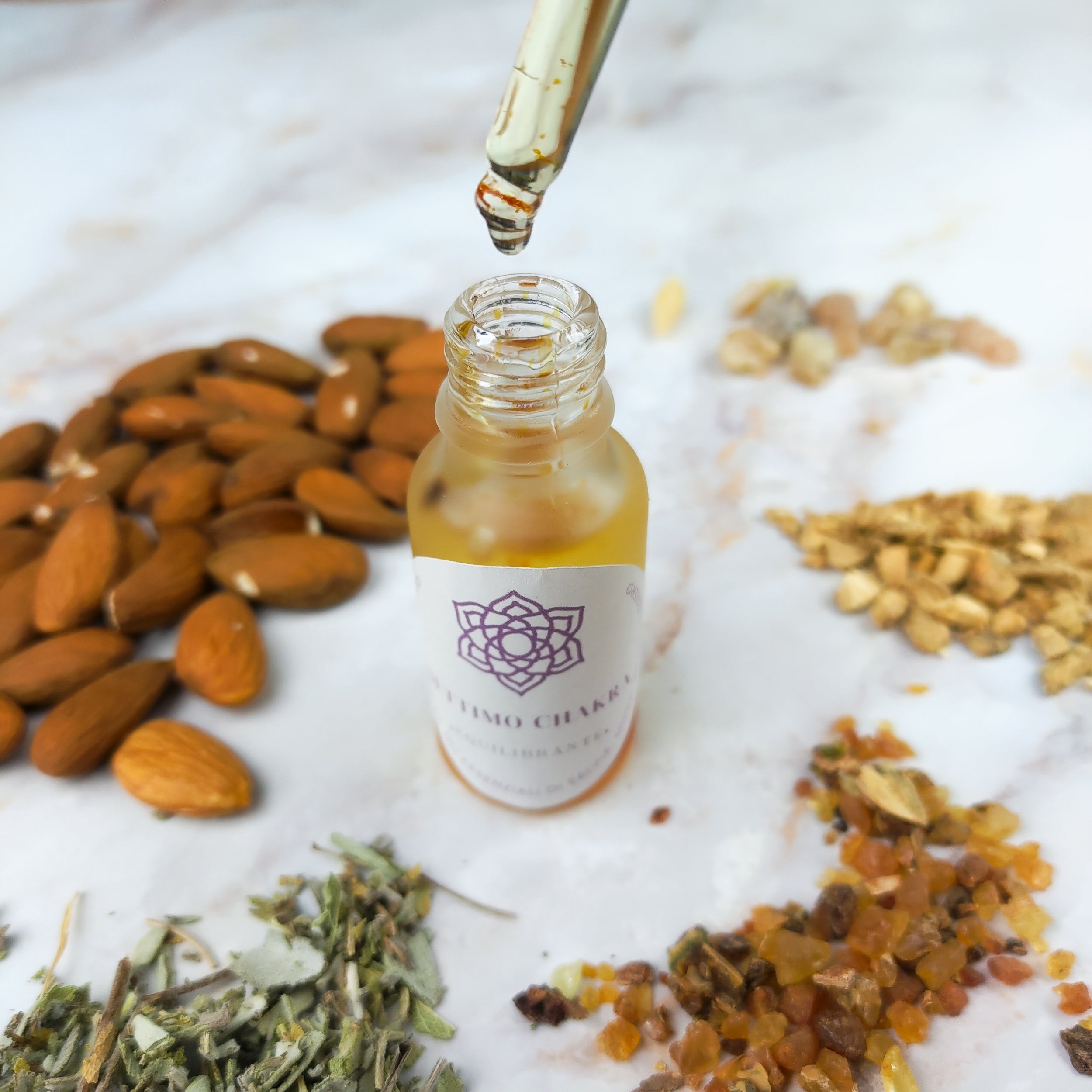 Olio per massaggi settimo chakra con ingredienti naturali e goccia in primo piano su sfondo di erbe e noci