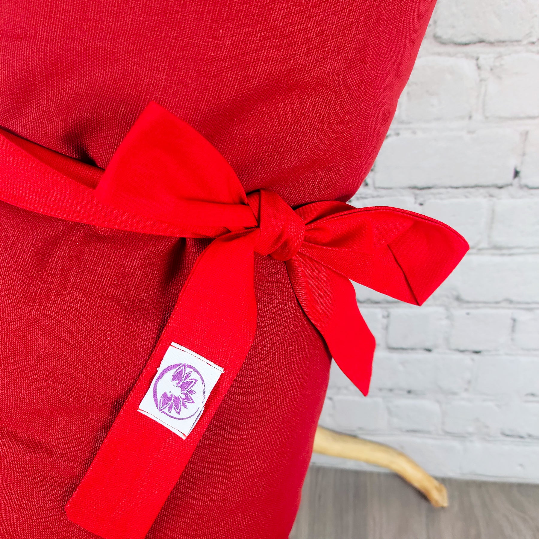 Cuscino lombare rosso con nastro e logo, ideale per la schiena e il tappetino zabuton rosso.