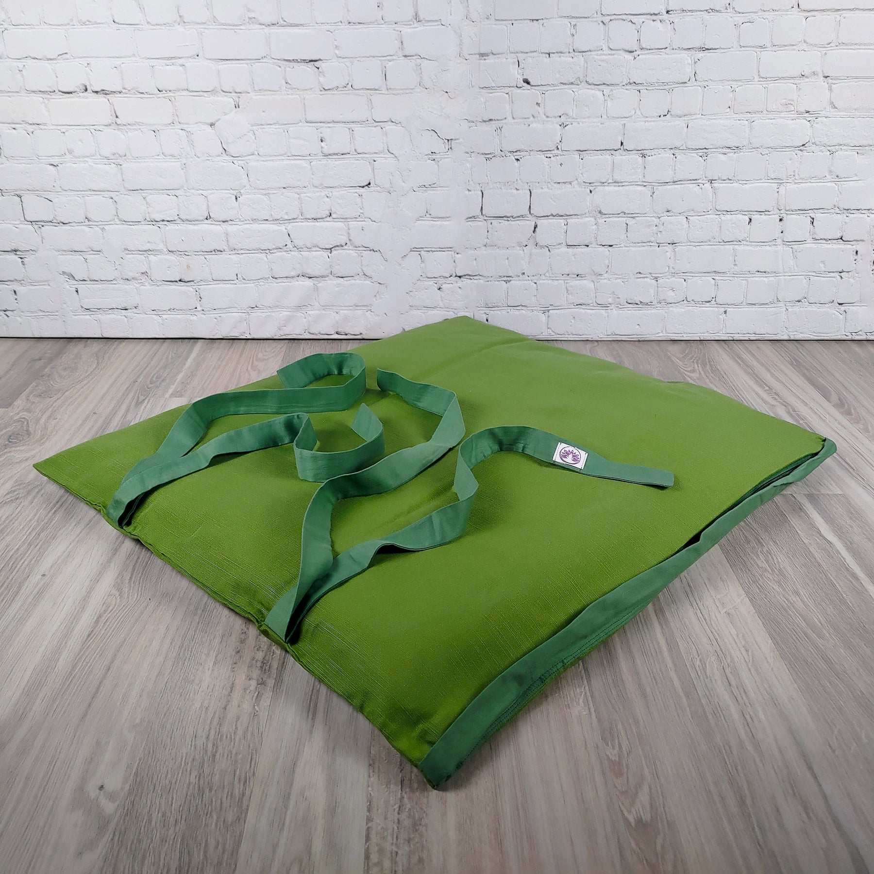 Cuscino di supporto lombare in verde con maniglie, ideale per il tappetino zabuton verde durante le pratiche di meditazione