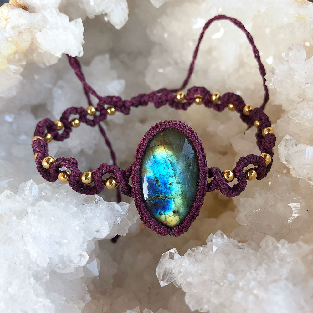 Bracciale macramé labradorite con dettaglio blu e oro su sfondo di cristalli bianchi