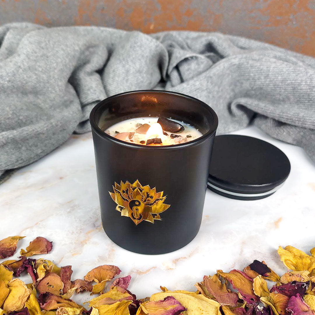 Candela con cristalli in contenitore nero con decorazione floreale e petali di rosa attorno