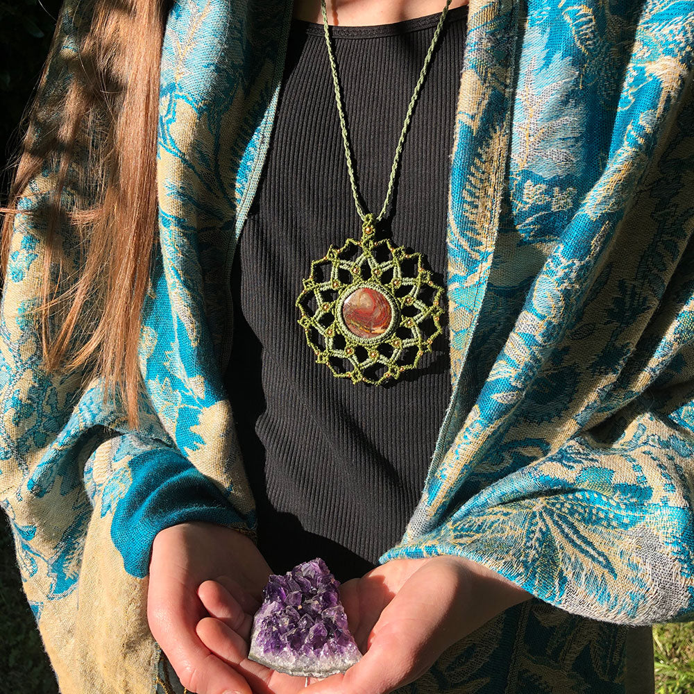 Collana mandala macramé verde con pietra arancione, indossata da una donna con un&