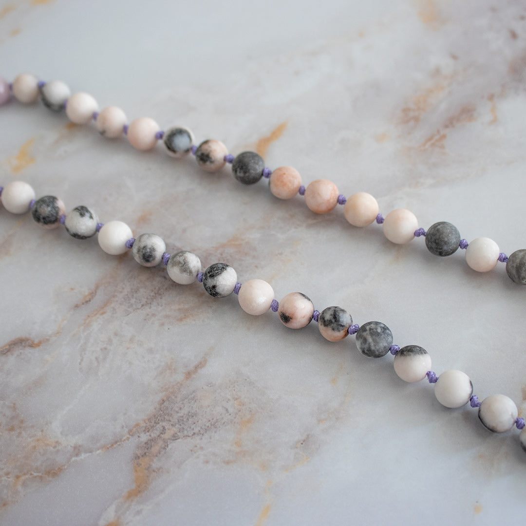 Collana mala kunzite diaspro con perle in tonalità pastello su sfondo marmoreo