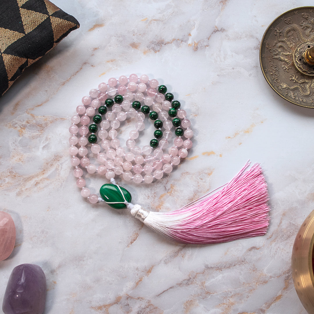 Collana mala malachite e quarzo rosa con tassello frangi e perline colorate su sfondo elegante