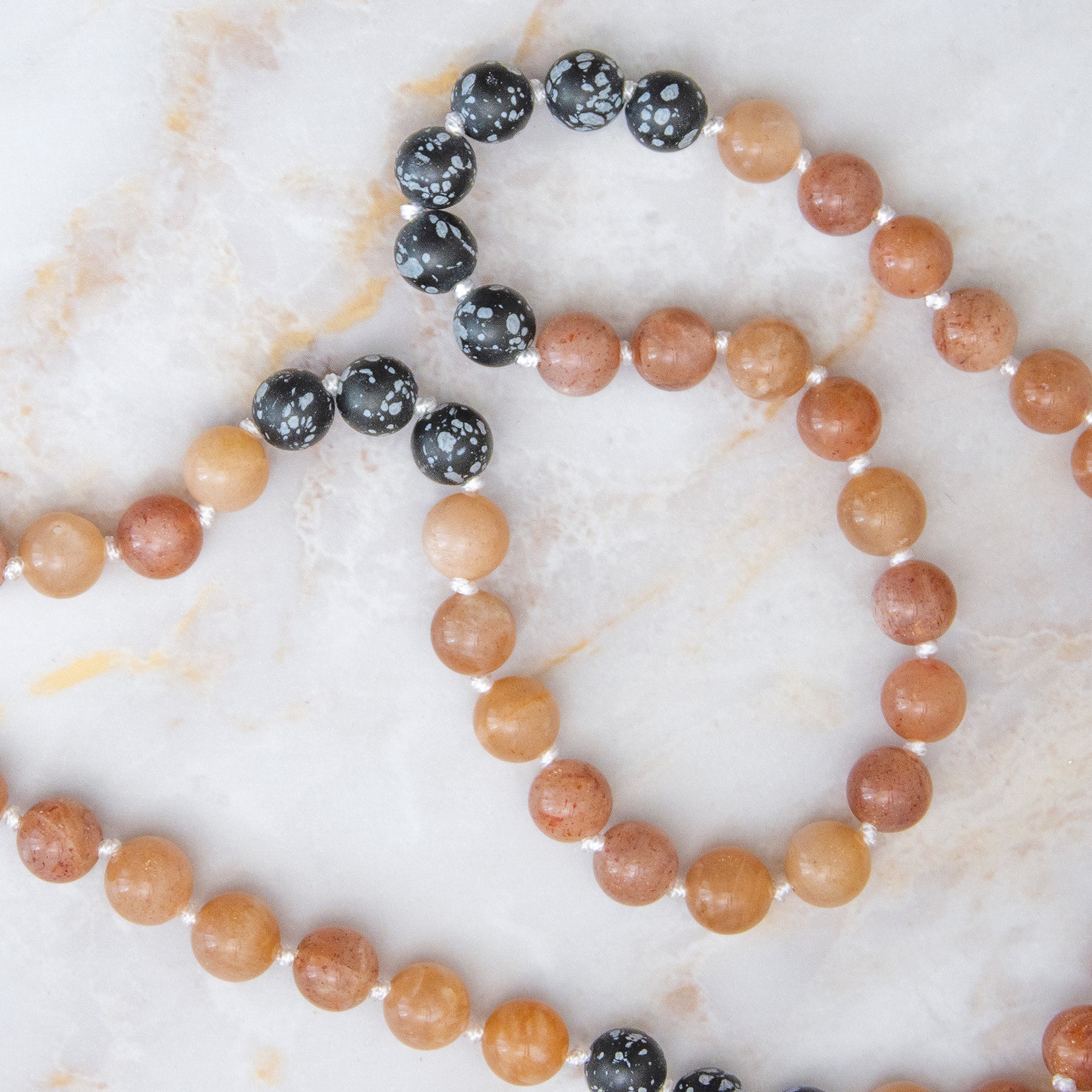 Collana mala pietra del sole diaspro con perle di diaspro e ossidiana su sfondo marmoreo