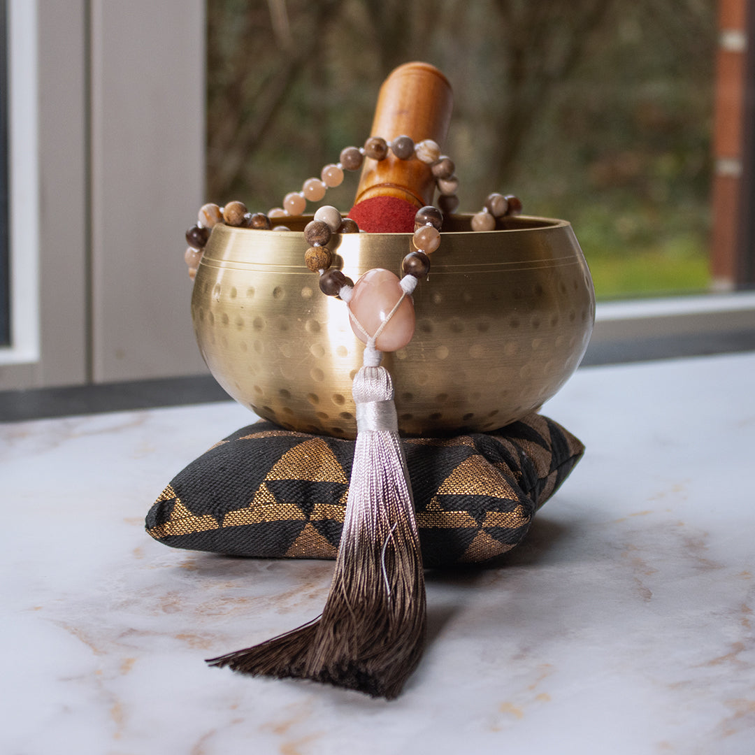 Collana mala pietra del sole e legno con dettagli in filo a nastro su un cuscino decorativo