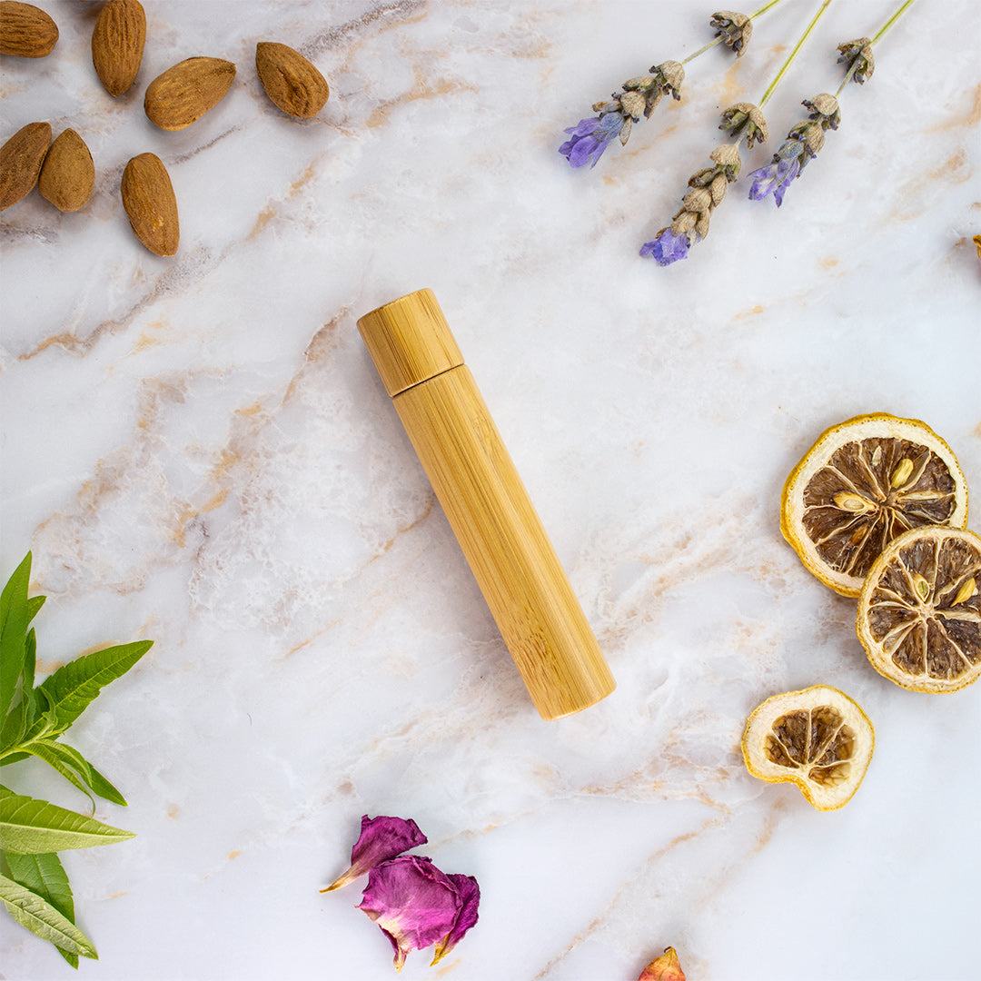 Olio naturale anti insetti in un flacone di bambù circondato da mandorle e fiori secchi