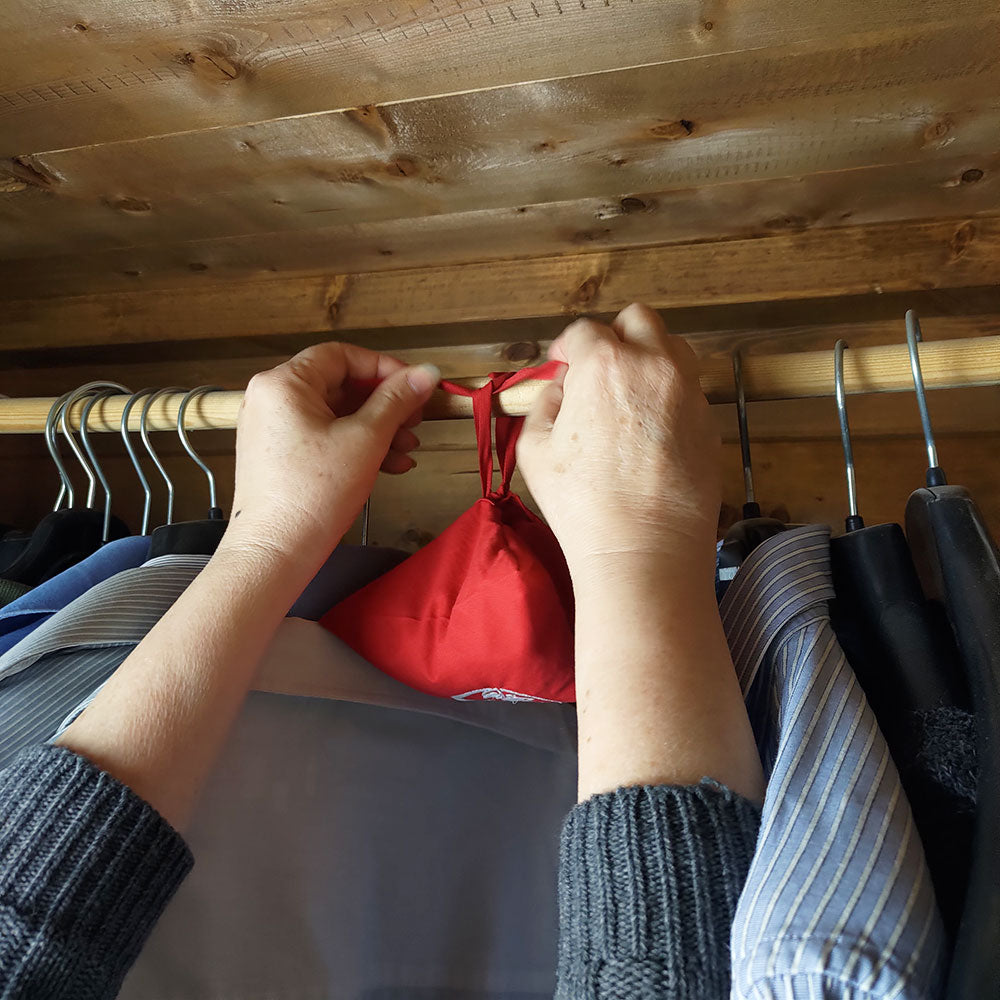 Profumatore ambiente quinto chakra in uso, appeso vicino ad abiti in un guardaroba di legno