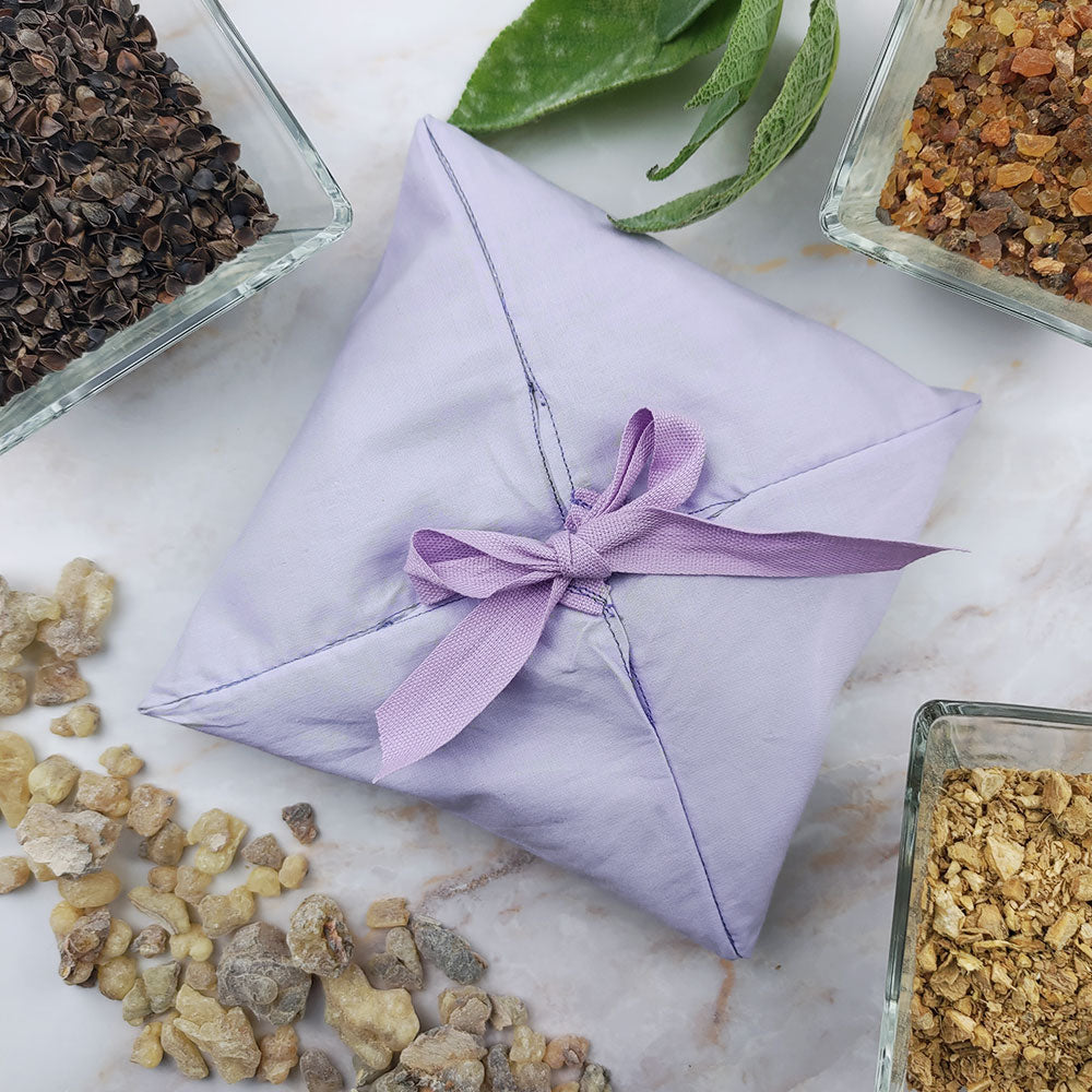 Profumatore ambiente settimo chakra avvolto in tessuto viola con aromi naturali circostanti