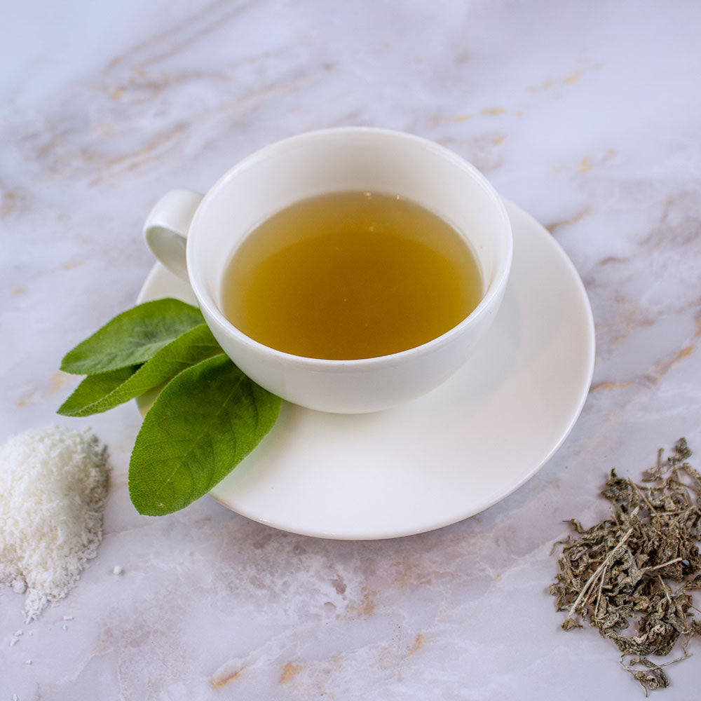 Tazza bianca di tisana con foglie fresche e ingredienti sulla superficie, set completo tisane chakra