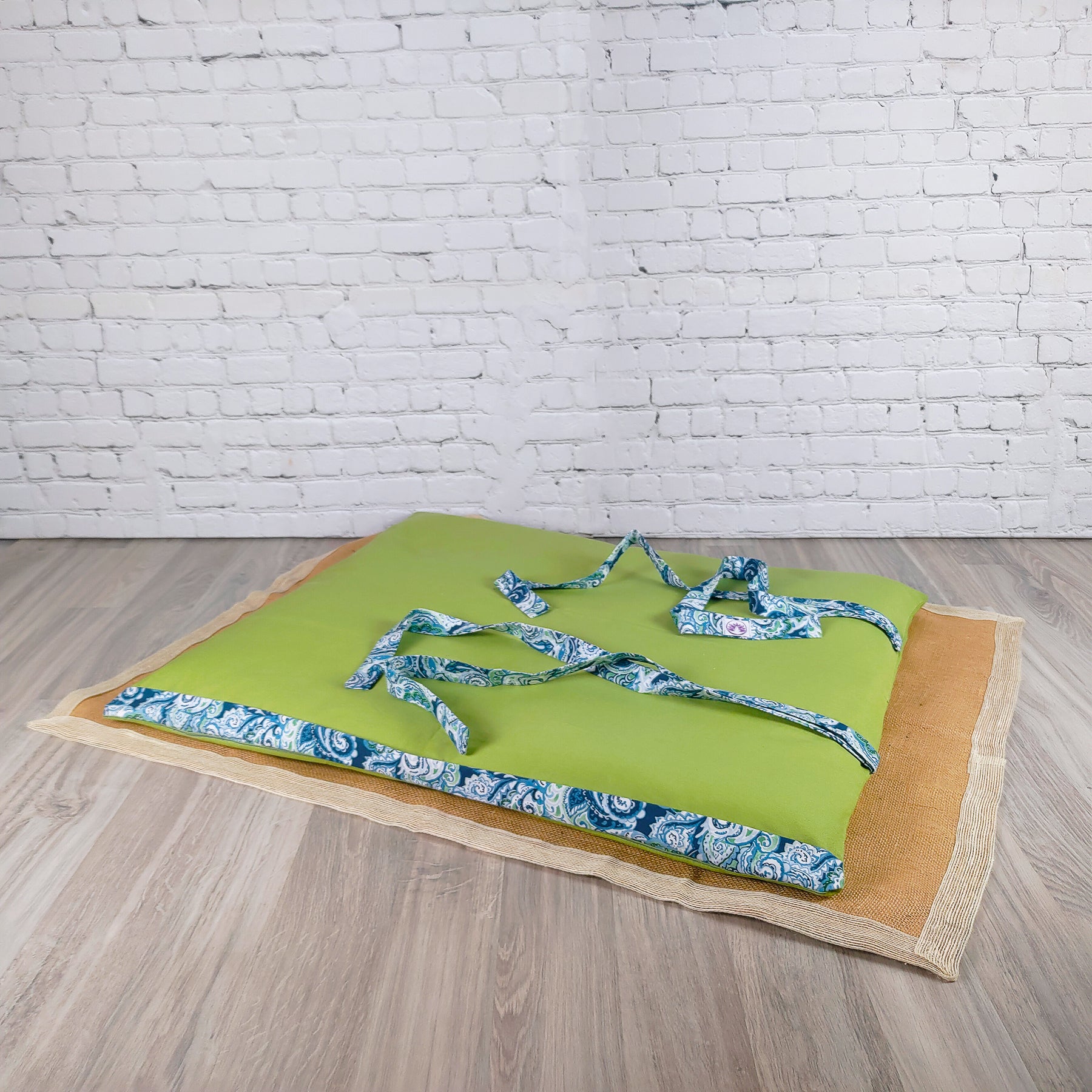 Stuoia da spiaggia verde con cinghie decorative azzurre, perfetta per il relax al mare