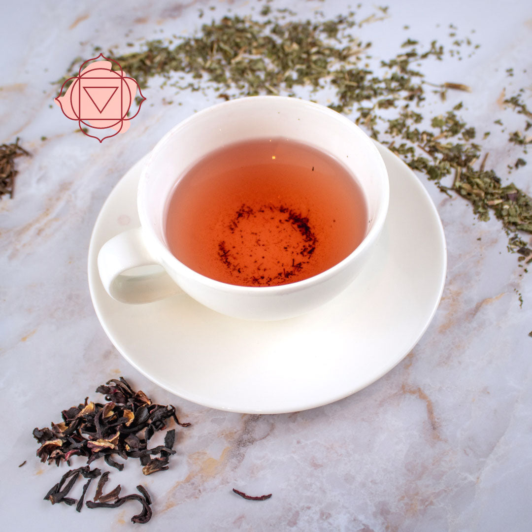 Tisana primo chakra servita in una tazza bianca con erbe aromatiche sullo sfondo