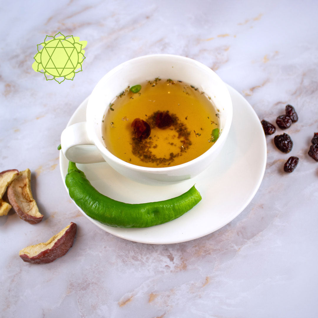 Tisana quarto chakra servita in una tazza bianca con foglie verdi e frutti secchi