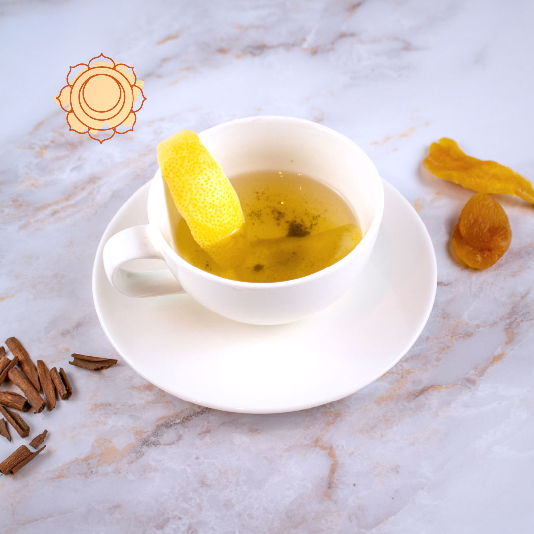 Tisana secondo chakra servita in una tazza bianca con limone e frutta essiccata in primo piano