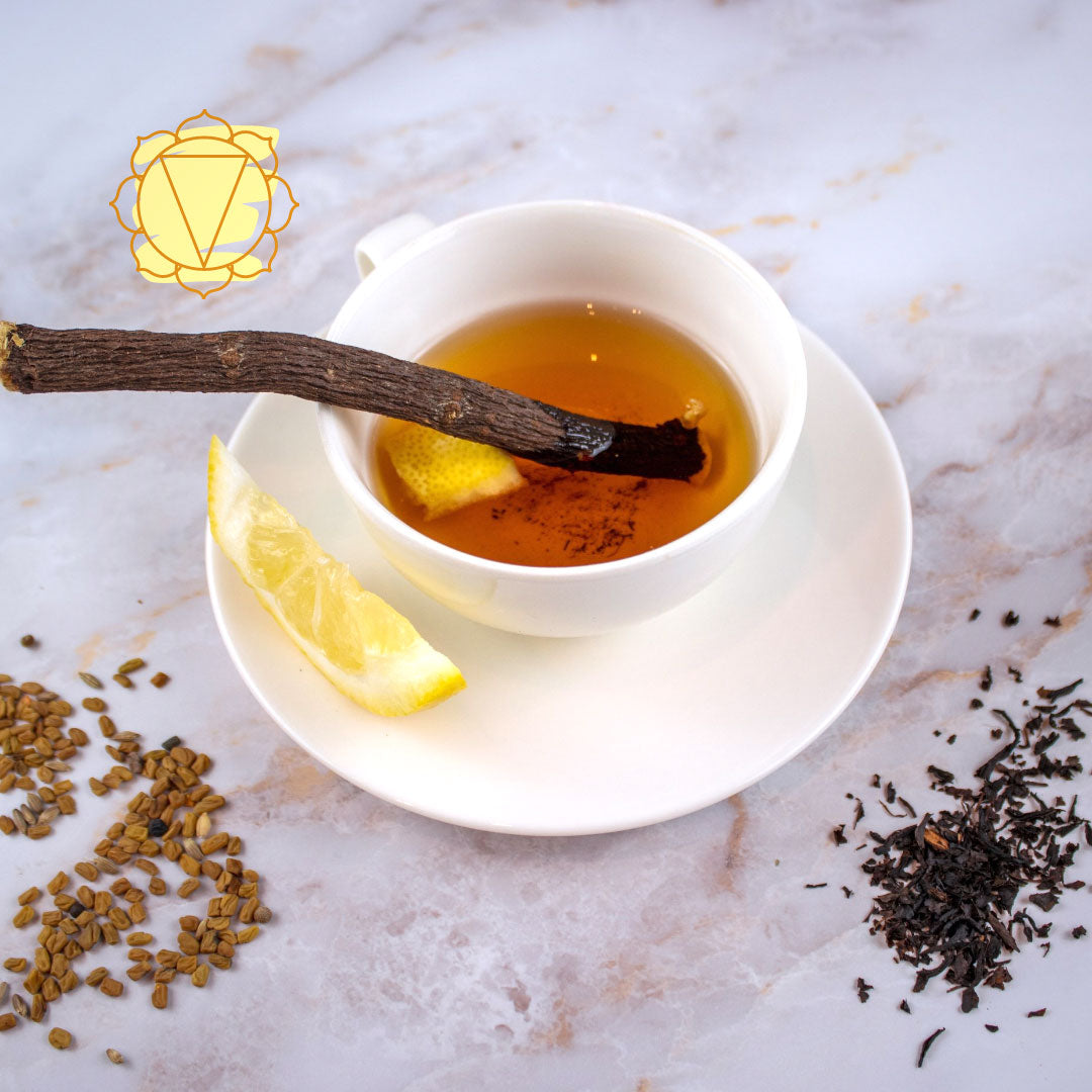 Tisana Terzo Chakra in tazza bianca con limone e stecca di cannella su sfondo di spezie