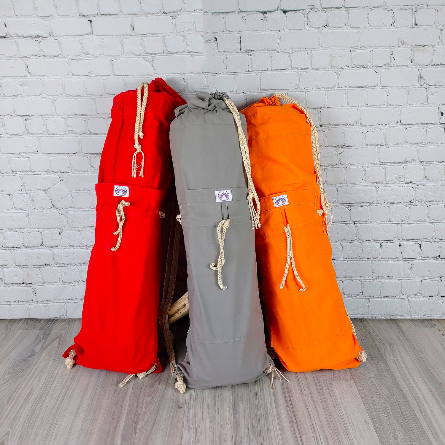 Tre borse porta tappetino yoga in rosso, grigio e arancione con tasche laterali e chiusura cordino
