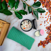 Confezioni regalo con box benessere artigianale, candele, e prodotti naturali su un tavolo decorato