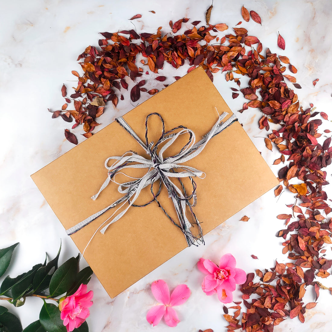 Confezione regalo box benessere artigianale con nastri e fiori sullo sfondo naturale