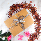 Confezione regalo box benessere artigianale con nastri e fiori sullo sfondo naturale