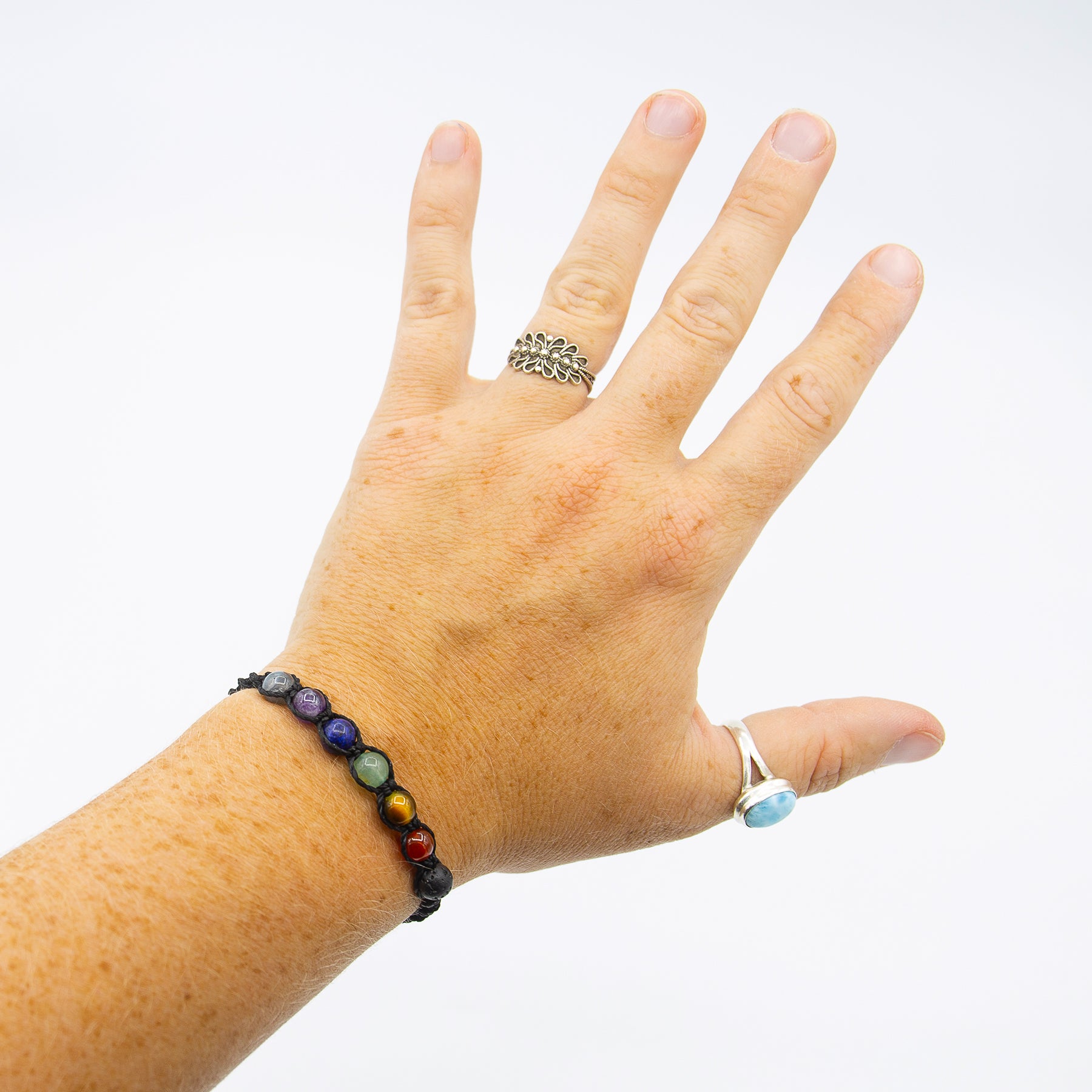 Bracciale chakra macramé con perline colorate indossato su una mano aperta