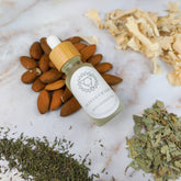 Olio per massaggi quinto chakra in bottiglietta con contagocce su sfondo di erbe e mandorle