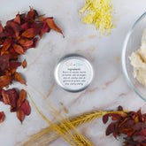 Burro labbra naturale in vaso con ingredienti come burro di karité e olio di argan su sfondo marmoreo.