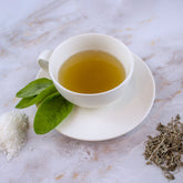 Tazza bianca di tisana con foglie fresche e ingredienti sulla superficie, set completo tisane chakra